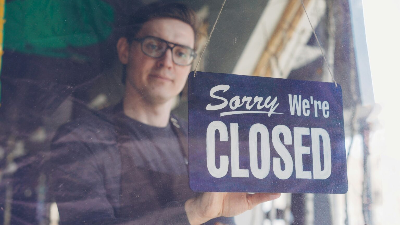 Business owner holding a closed sign, symbolizing why startups fail and shut down in the first 5 years.